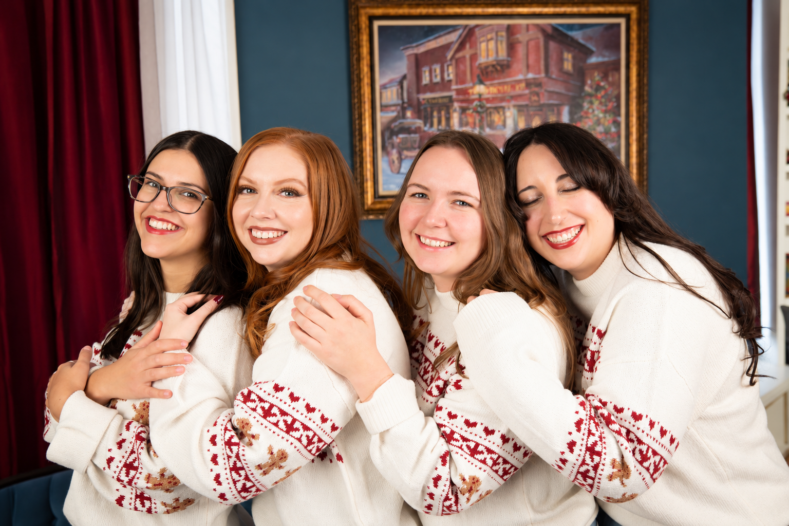 Four women in matching Christmas sweaters posing beside a decorated tree at Drummond Manor in Waterdown